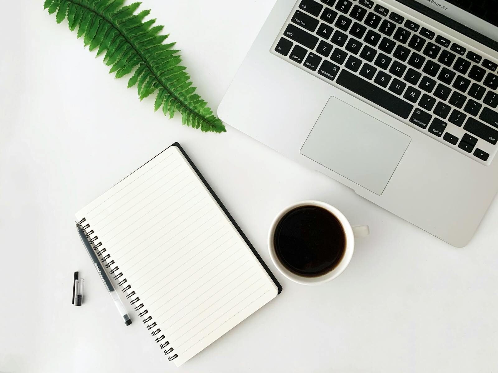From above creative design of workplace with mug of coffee near modern netbook and open notepad